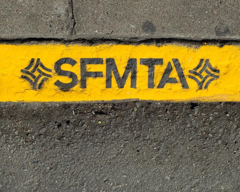Image of yellow zone curb with SFMTA lettering displayed