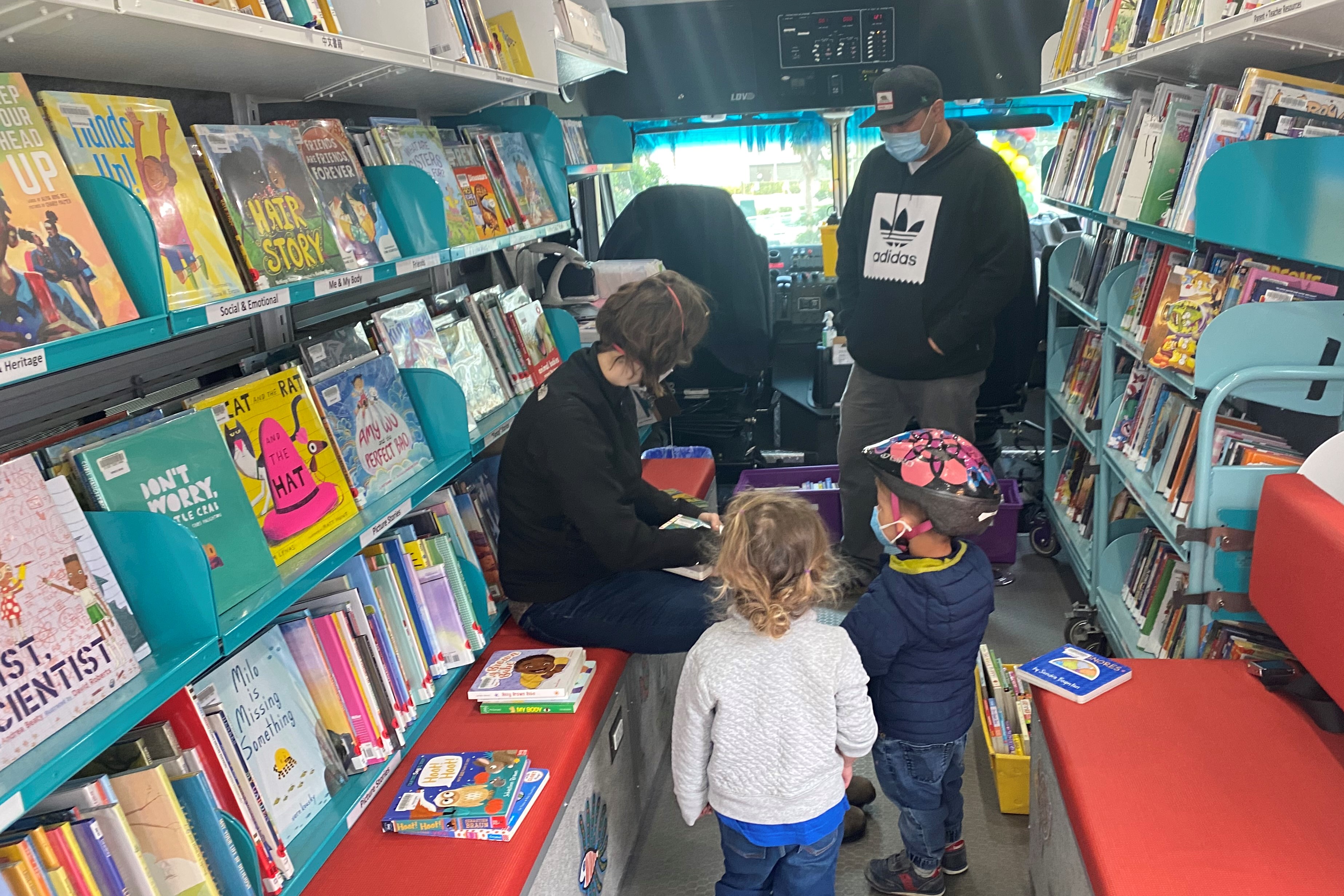 Adults and children look at books inside the Bookmobile