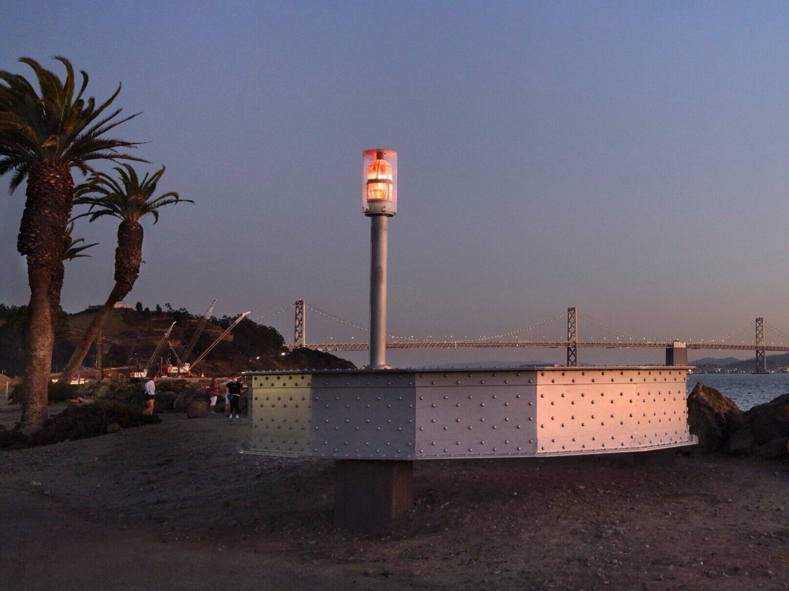 The artwork Signal is pictured along the Treasure Island shoreline, palm trees are behind the artwork
