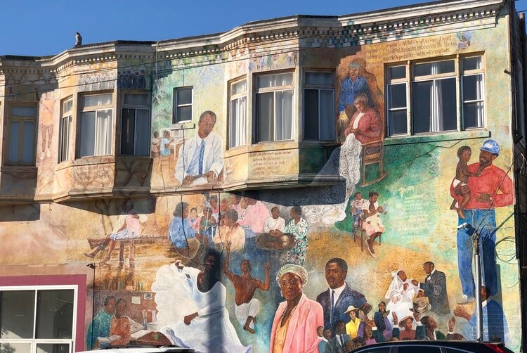 Photo depicts a mural of Black and African American figures painted on the side of a building
