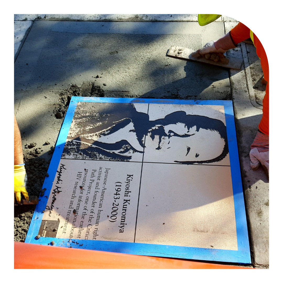 Photo of a rainbow plaque being installed in the Castro sidewalk