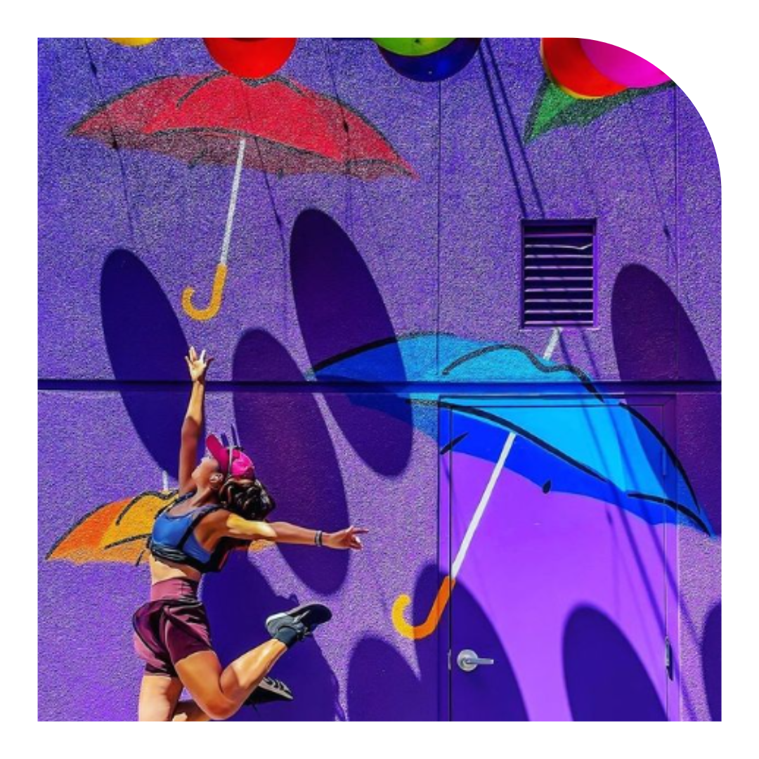 Photo of person jumping with a mural of umbrellas in the background