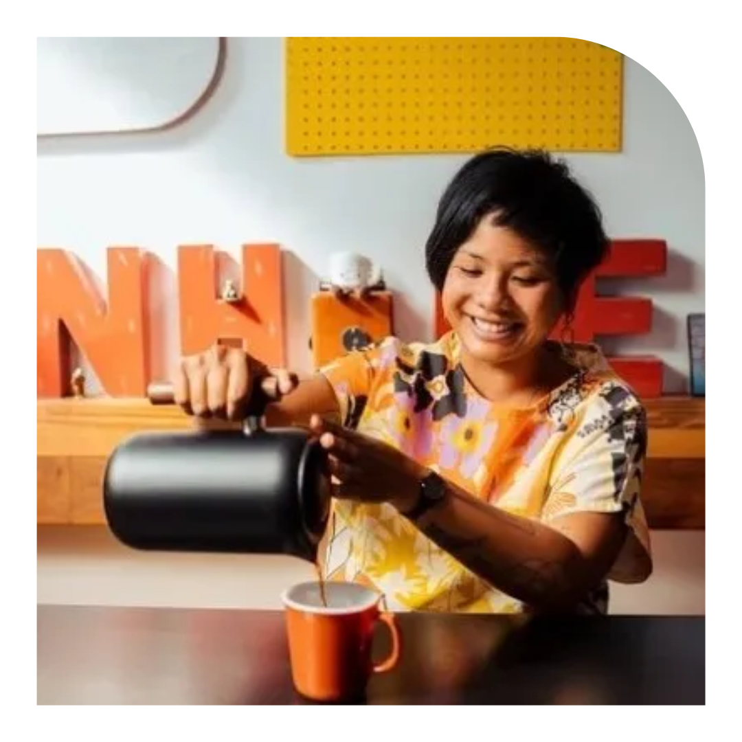 photo of a person smiling pouring a cup of coffee