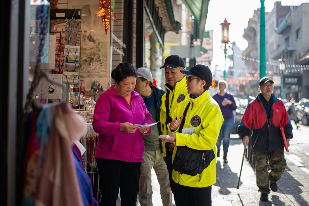 Two Community Ambassadors interact with a local business owner in Chinatown