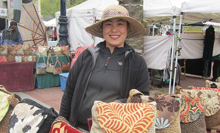 Individual in front of a table selling homemade bags