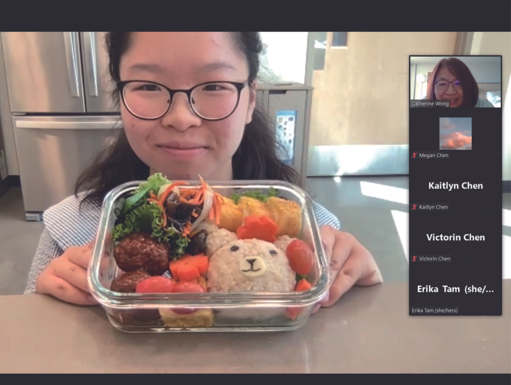 A young person shows the colorful bento box vegetable stir-fry they made that includes a  a rice ball in the shape of a bear while program participants look on over Zoom