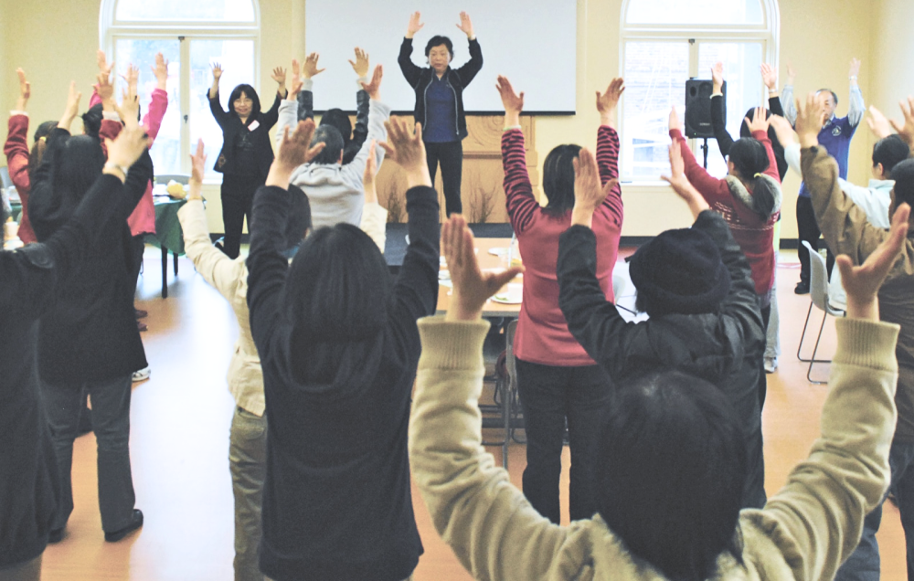 An instructor leads an exercise class with people wearing comfortable clothing.