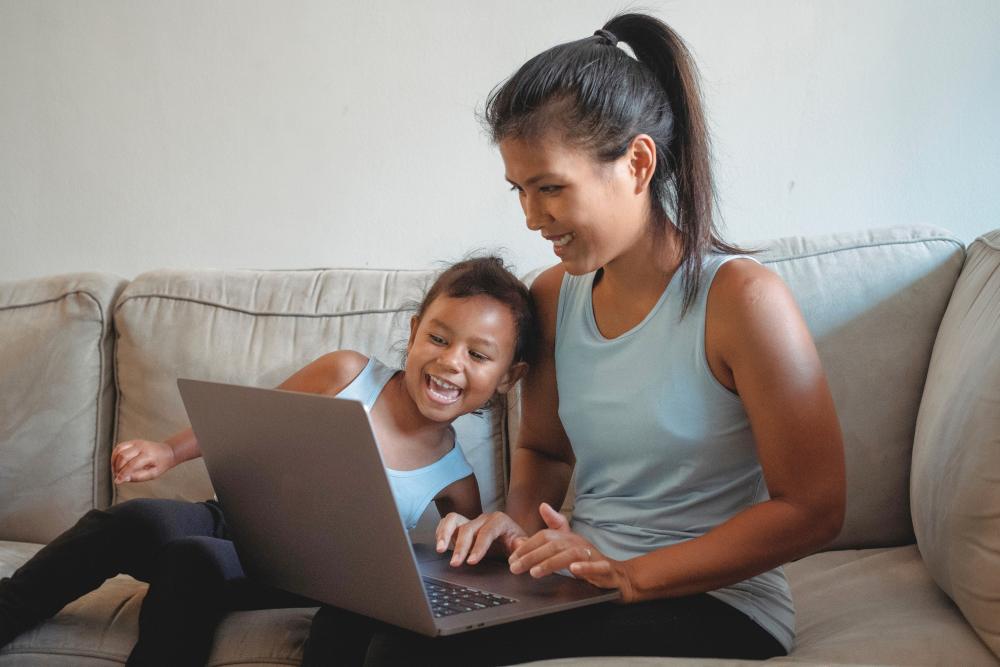 Mother and daughter with computer sitting on couch