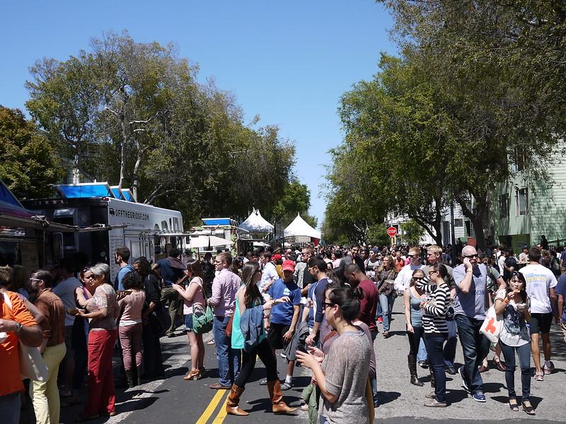 A crowd of people standing near food trucks at a San Francisco street fair