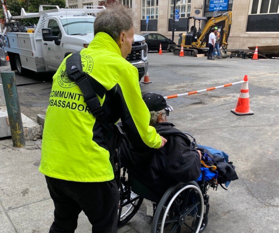 A Community Ambassador provides a safety escort to a resident using a wheelchair.